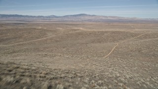 AX0005_069E - 5K aerial stock footage fly low over open desert and arid hills to reveal solar array in Antelope Valley, California