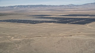 AX0005_097 - 5K aerial stock footage of fly over desert mountain and reveal solar energy array in the Mojave Desert, California