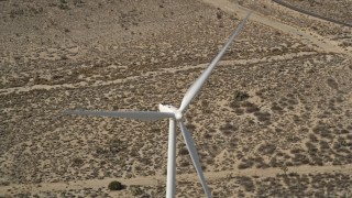 5K aerial stock footage tilt to bird's eye view of a windmill at a desert wind farm in California Aerial Stock Footage | AX0006_015