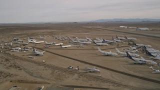 AX0006_077 - 5K aerial stock footage of large and small airplanes at a boneyard in the desert, Mojave Air and Space Port, California