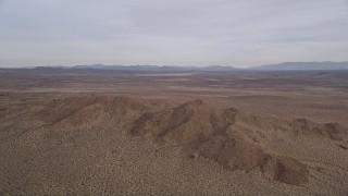 5K aerial stock footage of panning across open desert to reveal and approach mountains, Mojave Desert, California Aerial Stock Footage | AX0006_115