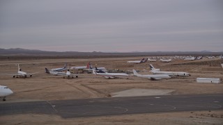 AX0007_003E - 5K aerial stock footage of low altitude orbit around airliners at the Victorville Airport boneyard in California at Sunset