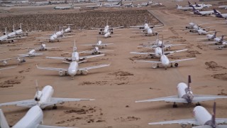 AX0007_010 - 5K aerial stock footage of rows of cargo planes at an aircraft boneyard at Sunset, Victorville Airport, California