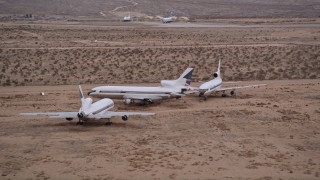 AX0007_011 - 5K aerial stock footage orbit a trio of airliners at Sunset at an aircraft boneyard, Victorville Airport, California