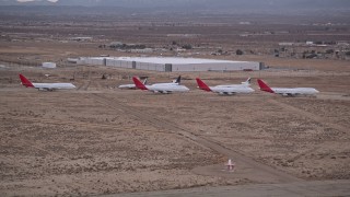 AX0007_012 - 5K aerial stock footage approach group of airliners at Sunset in an aircraft boneyard, Victorville Airport, California