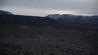 5K aerial stock footage fly over Mojave Desert and approach mountains with light snow at twilight, California Aerial Stock Footage | AX0007_045