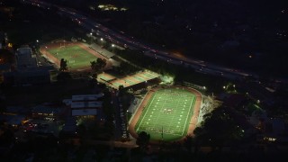 AX0008_067E - 5K aerial stock footage approach and orbit football and track fields at night in La Cañada Flintridge, California