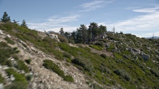 AX0009_045E - 5K aerial stock footage of flying up a rocky slope in the San Gabriel Mountains, California to reveal distant mountains