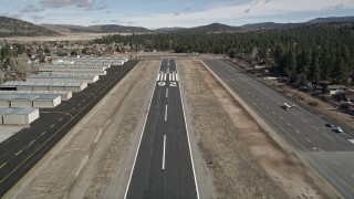 AX0010_001 - 5K aerial stock footage liftoff from the eunway at Big Bear City Airport, California