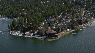 AX0010_025 - 5K aerial stock footage orbit large waterfront homes on the shore of Big Bear Lake with light winter snow, California