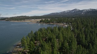 5K aerial stock footage tilt to reveal and approach shore of Big Bear Lake with light winter snow, California Aerial Stock Footage | AX0010_036