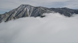 5K aerial stock footage tilt from snowy mountain to reveal tall peak in the San Jacinto Mountains in winter, California Aerial Stock Footage | AX0010_093