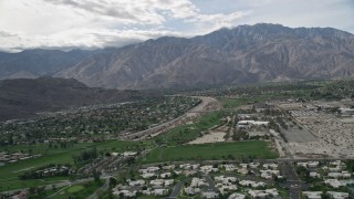 AX0010_142 - 5K aerial stock footage of suburban neighborhoods in West Palm Springs near tall mountain range, California