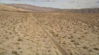 5K aerial stock footage approach and fly over a silver sedan on a lonely desert road in Joshua Tree National Park, California Aerial Stock Footage | AX0011_007