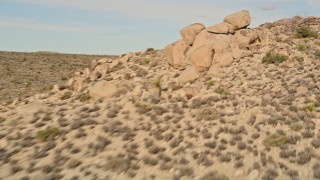 AX0011_035 - 5K aerial stock footage pan past Joshua Trees and over rock formations, Joshua Tree National Park, California