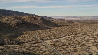 AX0011_045 - 5K aerial stock footage of flying by a winding desert road, Joshua Tree National Park, California