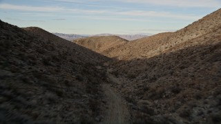 5K aerial stock footage of flying over a dirt road through a desert canyon, Mojave Desert, California Aerial Stock Footage | AX0011_055E