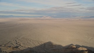 AX0011_064 - 5K aerial stock footage fly low over a mountain revealing desert plain, Mojave Desert, California