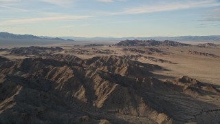 AX0011_070 - 5K aerial stock footage fly by mountains revealing desert plain, Mojave Desert, California