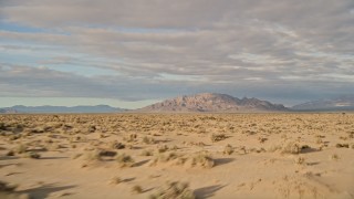 AX0012_001 - 5K aerial stock footage fly low over desert toward mountains, Mojave Desert, California