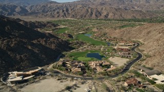 AX0013_082 - 5K aerial stock footage fly over upscale homes toward golf course among mountains, Indian Wells, California