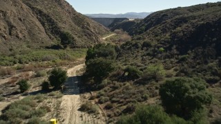 AX0014_029E - 5K aerial stock footage of following a dirt Road leading to Hemet Dam, California