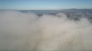 5K aerial stock footage fly over a dense cover of clouds below blue skies, reveal tract homes in Oceanside, California Aerial Stock Footage | AX0015_055E