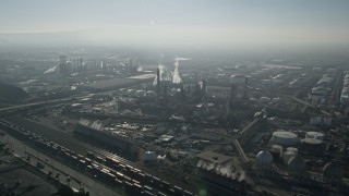 AX0017_002E - 5K aerial stock footage of approaching an oil refinery with smoke stacks, Carson, California