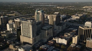 AX0018_004E - 5K aerial stock footage fly over Lake Eola to approach office buildings and arena in Downtown Orlando at sunrise, Florida