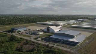 AX0018_064 - 5K aerial stock footage of passenger jet and hangars at Melbourne International Airport at sunrise in Florida