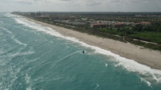 AX0019_041E - 5K aerial stock footage approach kite surfer by the beach in Jupiter, Florida