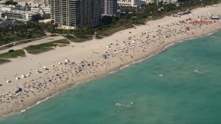 AX0020_047 - 5K aerial stock footage of large group of sunbathers and beachgoers by the ocean in South Beach, Florida