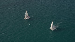 5K aerial stock footage tilt from calm ocean water to reveal and orbit two catamarans near South Beach, Florida Aerial Stock Footage | AX0021_037E