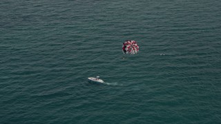 AX0021_054E - 5K aerial stock footage of parasailer gliding over the ocean near South Beach, Florida