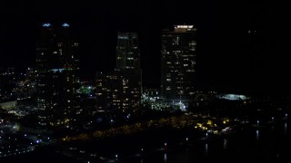 AX0023_065E - 5K aerial stock footage approach and orbit Portofino Tower and skyscrapers in South Beach at night, Florida