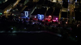 AX0023_075 - 5K aerial stock footage tilt from ocean to reveal and approach hotels at night in South Beach, Florida