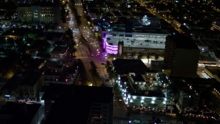 AX0023_112 - 5K aerial stock footage of shops and cafes on a busy intersection at night in South Beach, Florida