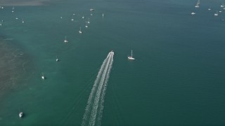 5K aerial stock footage of following a speedboat racing past moored sailboats, Key West, Florida Aerial Stock Footage | AX0026_083