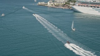 5K aerial stock footage of a speedboat racing across water and tilt to more boats in Key West, Florida Aerial Stock Footage | AX0026_099