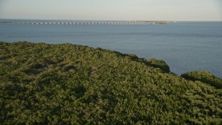 AX0028_017E - 5K aerial stock footage of flying over mangroves, revealing Overseas Highway bridge, Long Key, Florida, sunset