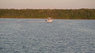 5K aerial stock footage of tracking a fishing boat racing past mangroves at sunset, Key Largo, Florida Aerial Stock Footage | AX0028_031E