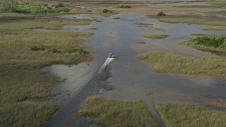 AX0030_064E - 5K aerial stock footage of tracking a fanboat racing through marshland, Florida Everglades, Florida