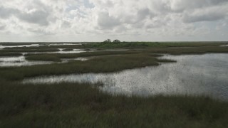 AX0030_078 - 5K aerial stock footage of flying low over marshes, revealing huts hidden in trees, Florida Everglades, Florida