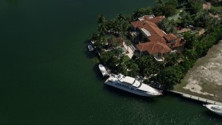 AX0031_009 - 5K aerial stock footage of flying by mansion, yacht docked in front, Coral Gables, Florida