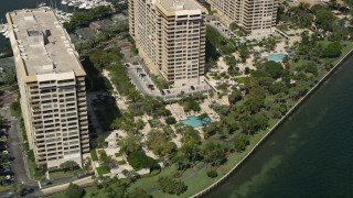 AX0031_017 - 5K aerial stock footage of flying by condo complexes with pools, Grove Isle, Florida