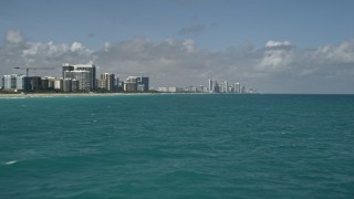 AX0031_067E - 5K aerial stock footage of flying over the Atlantic Ocean, revealing beachfront buildings, Sunny Isles Beach, Florida