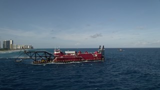 AX0032_112 - 5K aerial stock footage of orbiting a dredging ship, revealing the coast, Palm Beach Shores, Florida