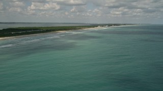 AX0033_023E - 5K aerial stock footage tilt up from blue ocean waters revealing beachfront homes, Fort Pierce, Florida