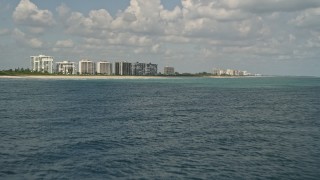 AX0033_042 - 5K aerial stock footage tilt up from blue ocean waters revealing beachfront apartment buildings, Fort Pierce, Florida