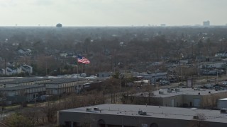 5K aerial stock footage of an American flag flying over warehouse buildings in Farmingdale, Long Island, New York Aerial Stock Footage | AX0065_0001